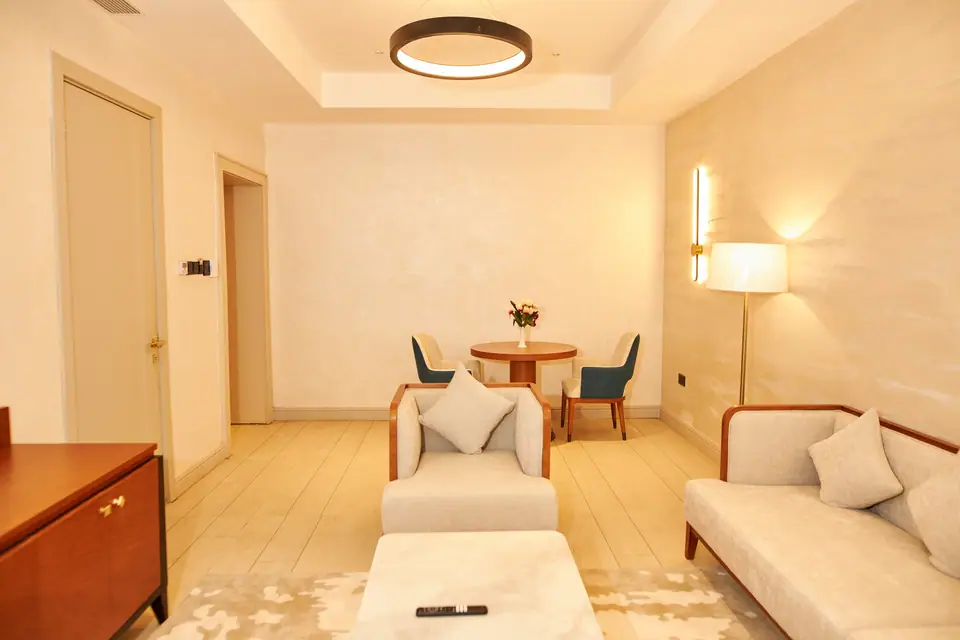Suite — open-plan living and dining area with circular pendant light, sofas and round dining table