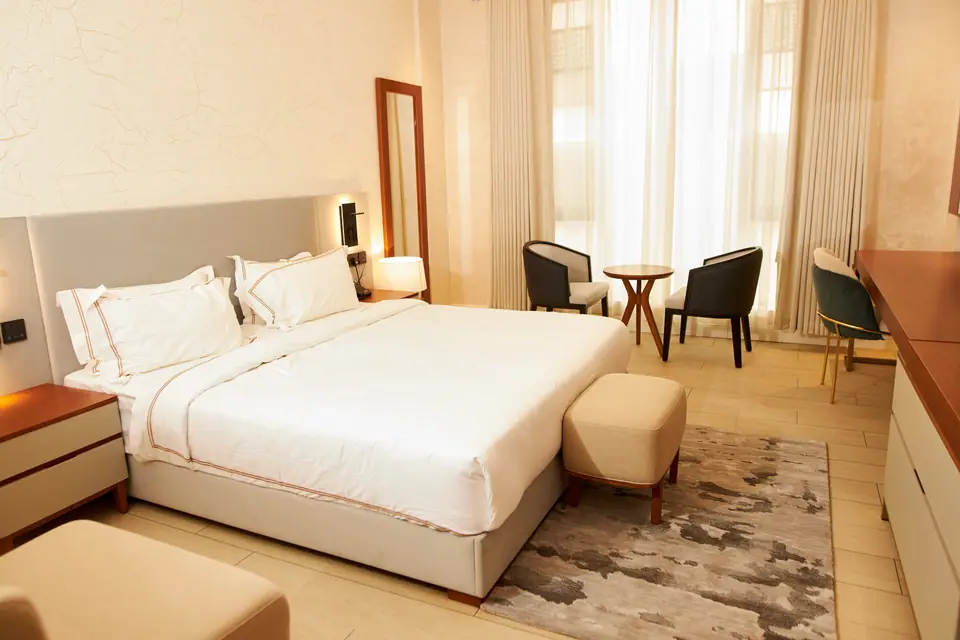 Super Deluxe — king bed with sheer curtains, sitting area and warm natural light